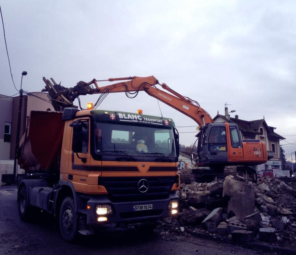 Suite à une démolition, une pelleteuse met des débris dans un camion benne